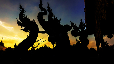 Silhouette dragon or naga statue against twilight sky at dawn at Wat Rong Sua Ten, Chiang Rai, Thailandの写真素材