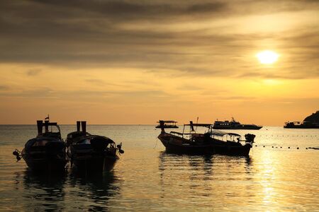 Silhouette scene of Thai wood motor boat on Andaman tropical sea at sunset in Koh Lipe, Satun, Thailand.の写真素材