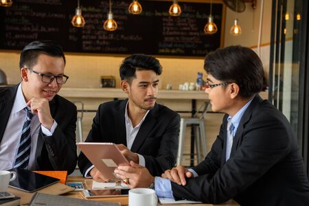 businessman team discuss with boss for project progress by using digital tablet in coffee cafe. Work at home Business concept by checking project plan used 4g technology.の写真素材