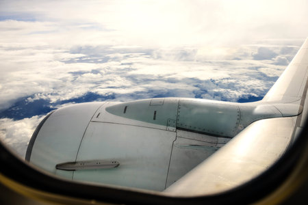 airplane wing against sky and clouds by the view of aircraft window. Transportation and travel...