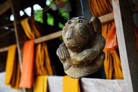 Wooden craft monkey hanging near Yellow monk rope at wooden priest house in Thailand.の写真素材