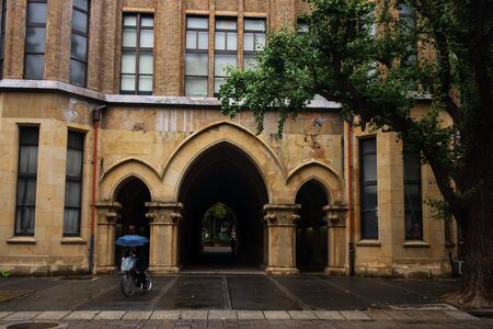 Man riding bicyle pass Path way of antique arch doors at University of Tokyo, Japan. Here, called Todai, is the first ranked research university in Asia.の写真素材