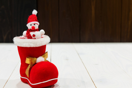 Happy snowman with red santa hat on xmas red sock and shoe with golden bow on white wood background with copy space for text. Christmas and 2018 new year decoration for celebration.の写真素材