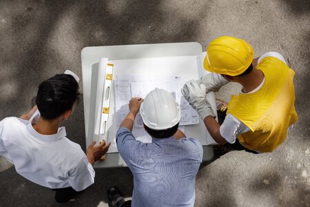 Top view of Engineering team of site manager, young field engineer, and foreman look paper plan at construction site,  Concept for team work of heavy industry.の写真素材