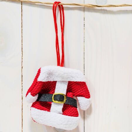 Santa Claus red dress or suit hanging on brown rope over rustic white wooden background. christmas and 2018 new year celebration with copy space for text for square photo.の写真素材