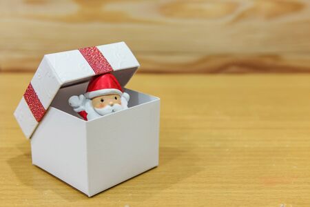 Santa claus in Xmas white gift box on brown wooden plank with copy space for text. Christmas and New year celebration concept for interior decoration and advertisement.の写真素材