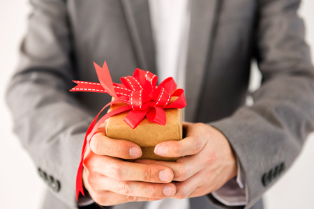 Businessman hands holding and giving a gift box wirh red bow ribbon isolated on white background. Christmas, 2018 New year, Valentine present. In love couple concept.の写真素材