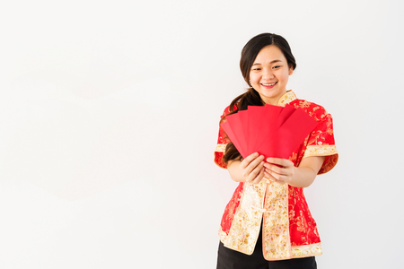 Happy beautiful Chinese woman dress traditional cheongsam costume and look at many red envelopes with money on white background. Asian girl get money on 2018 dog Chinese new year.の写真素材