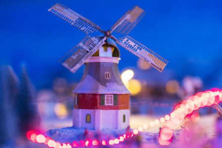 miniature houses with windmill in the village with snow at night with light up decoration. Christmas winter model for holiday background with copy space for text.の写真素材