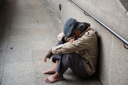 Old beggar or Homeless dirty man without shoes sitting and sleeping on walkway of modern city. feeling tired and hungry with copy space for text.の写真素材