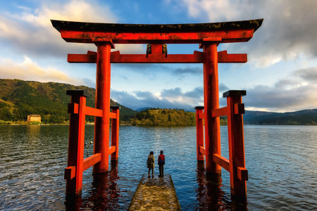 Japanese couple at red Torii gate of Hakone shrine located on lake Ashi, Japan. Gateways entrance to Shinto shrines and famous tourist landmark.のeditorial素材