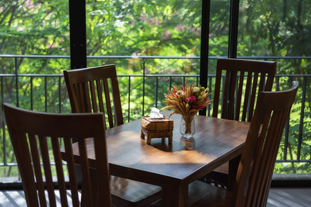 dinning table and fake flower decoration against greenery tree view and sunlightの写真素材