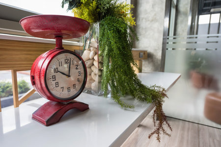 Antique red clock with fake plant and flower in glass decorated on modern table. Interior design