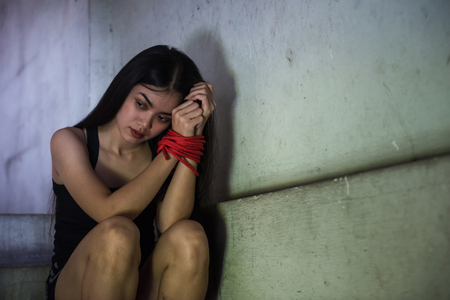 Depressed hostage woman hands tied red rope at stair of abandon house.  concept or victim female kidnapped from robber. Sexual abuse or rape with copy space for text.の写真素材