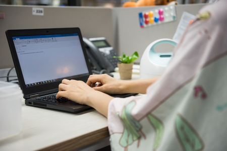 Busy working mother or mom typing on laptop pc computer on table and pumping breastmilk by Automatic breast pump machine with nursing fabric cover. Motherhood in corporate office.の写真素材