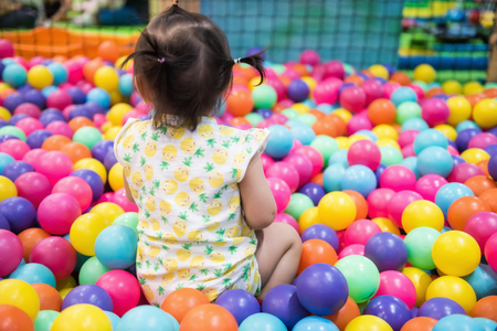 Rare shot of little girl having fun in ball pit with colorful balls. Child playing on indoor playground. Asian kid in ball pool.の写真素材