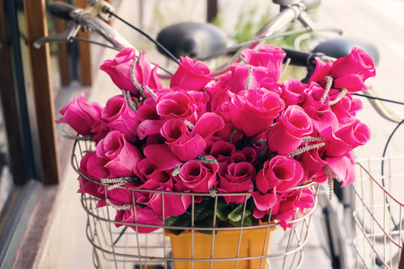 Pink fake flowers on front basket of vintage bicycle. Antiquw color tone.の写真素材