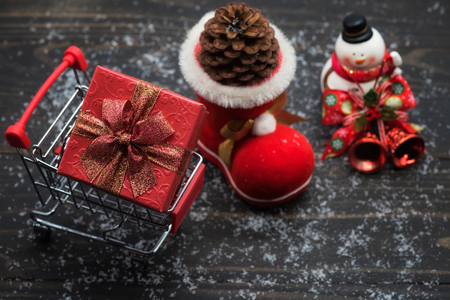 Christmas holiday shopping concept on wooden background with winter decoration of pine cones on santa sock, snow, xmas gift box on card, and snowman.の写真素材