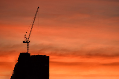 Silhouette crane and constructed building site with twilight sky at dusk. Heavy construction industry concept with copy space for text.の写真素材