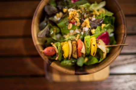 Grilled vegetables and healthy salad of fresh tomato, peanut, cucumber, onion, leà¸°tuce, lettuce and sesame by top view on wooden bowlの写真素材