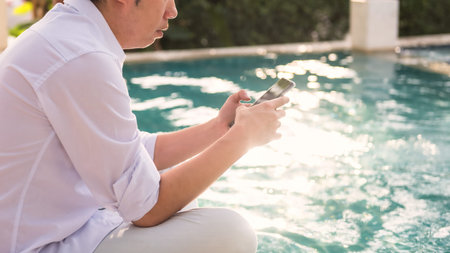 Asian businessman using smartphone or mobile phone to chat, play social media, shopping online at...