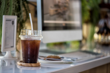 Iced black coffee (americano) with cookie on table with PC computer in modern coffee shopの写真素材