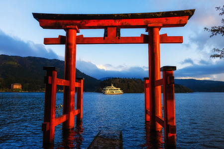 Red torii gate and tourist boat sailing in Lake Ashi at dusk, Hakone, Japanの写真素材
