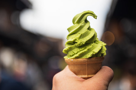 Japanese matcha green tea ice soft cream in hand with Takayama city and people bokeh background....