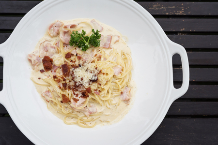 Spaghetti carbonara pasta with bacon and cheese on wooden table by top view. Italian famous food with copy space for text.の写真素材