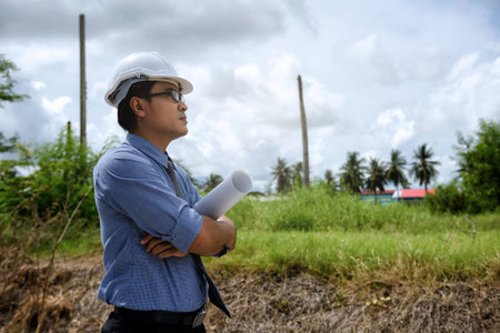 Senior Asian engineer manager looking at empty construction area at site. Start constructed project...