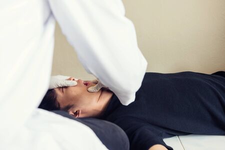 Doctor or detective open mouth to check pills during  performing autopsy or postmortem of death young man by overdose. Drug addiction and social issue for teenager, student, and worker.の写真素材