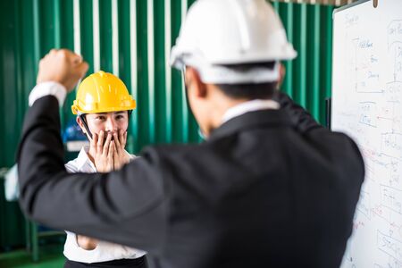 Panic factory female worker blame and shout by her boss manager for manufacturing plan delay. Depress, stress, anxious, serious in working industry, Unemployed, Fired, and lay off concept.の写真素材