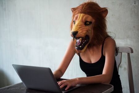 drug selling on gray trade business over the internet. Female woman agent with lion mask using laptop computer to trafficking narcotic or heroin. Abuse, Crime, and dope illegal concept against law.の写真素材