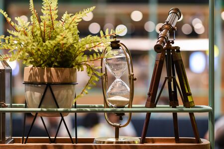 telescope, sand clock, fake plant on flower pot decoration with blurred light bokeh background. Restaurant or house interior design.の写真素材