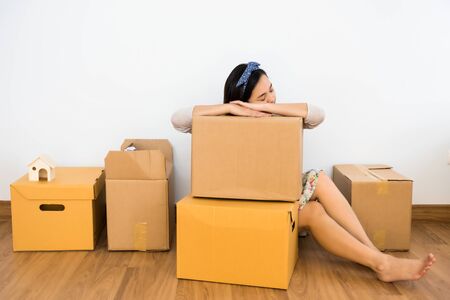 Tired Asian woman sleep on cardboard carton box after moving to new house. Wife move to new empty home to start family life. Architecture and Real estate industry.の写真素材