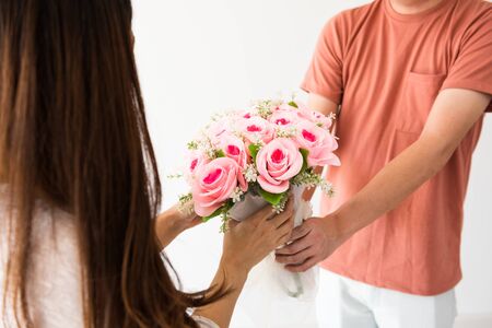 Closeup boyfriend hands giving rose flower bouquet to his girlfriend over white background and copy space for text. Happy couple celebrate 2020 Valentine day.の写真素材