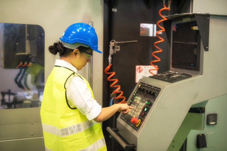 Waist up female engineer worker with hardhat and protection glasses press keyboard button to command...