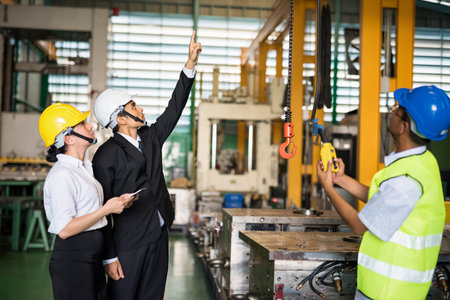 Factory manager point finger and command technician Asian worker to use remote control panel for...