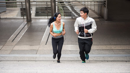 Happy Asian couple jogging upstair at modern city. people exercise cardio climbing staircase and...