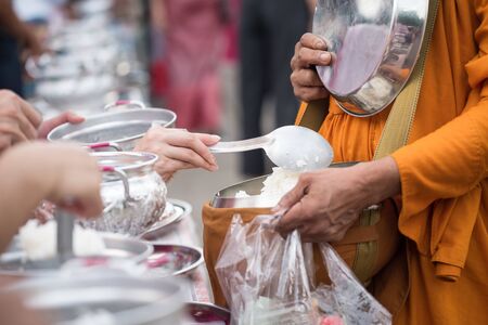 people offer jasmine rice to buddhist monk alms-bowl at early morning in sangkhlaburi district, Kanchanaburi, thailand. Famous travel activity and landmark here.の写真素材