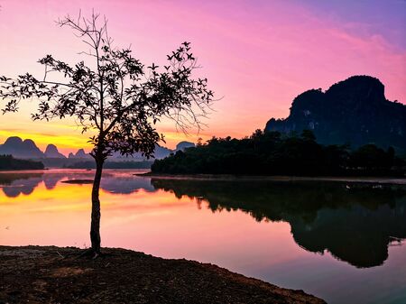 Natural Scenic view of tree, beautiful Limestone mountains, and reflection on water pond at dawn with twilight sky, NongTalay, Krabi, Thailand. Famous travel destination in Thai southern.の写真素材