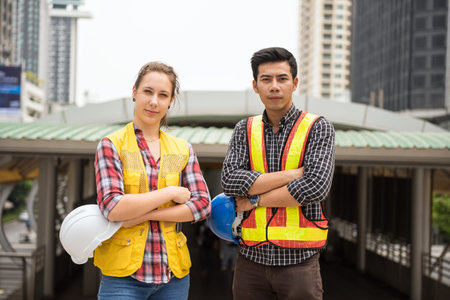 Happy Engineer team of Asian man and beauty American woman with safety helmet working on...