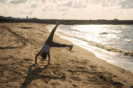Asian athlete woman in running outfit suit somersault on Rayong beach at sunrise in early morning,...