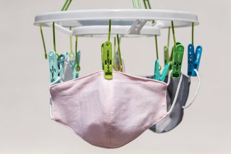 Reuse pink fabric face mask wash and hang in sunny day to terminate coronavirus by UV sunlight on white. Recycle tools to prevent covid-19 disease. Quarantine, Social distance, new normal, wfh.の写真素材