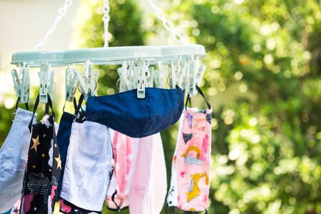 Closeup kid fabric face masks hang to dry in sunny day with blur foliage sunset bokeh green garden background. Reuse to prevent covid-19 or coronavirus. New normalの写真素材