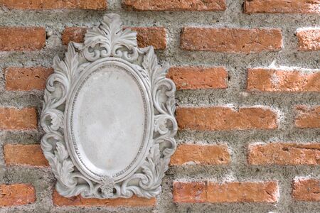 Antique white picture  or mirror frame decorated on old orange brick wall. Decor and exterior design for modern garden.の写真素材