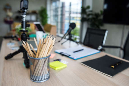 Accessories for work from home and social distancing. pencil , notebook, video camera on tripod, black microphone, tablet on table for vdo streaming live for blogger, online selling, education class.の写真素材