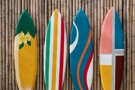 Many different colorful surfboards standing in a row on bamboo wooden wallの写真素材