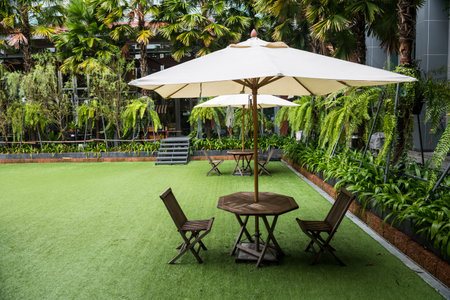 White Umbrella within chairs and amazing garden in outdoor resort and hotel.