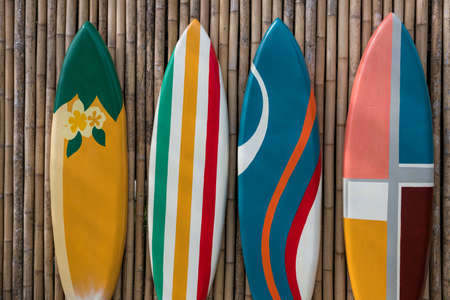 colorful paint surfboards standing in a row on bamboo wooden wallの写真素材